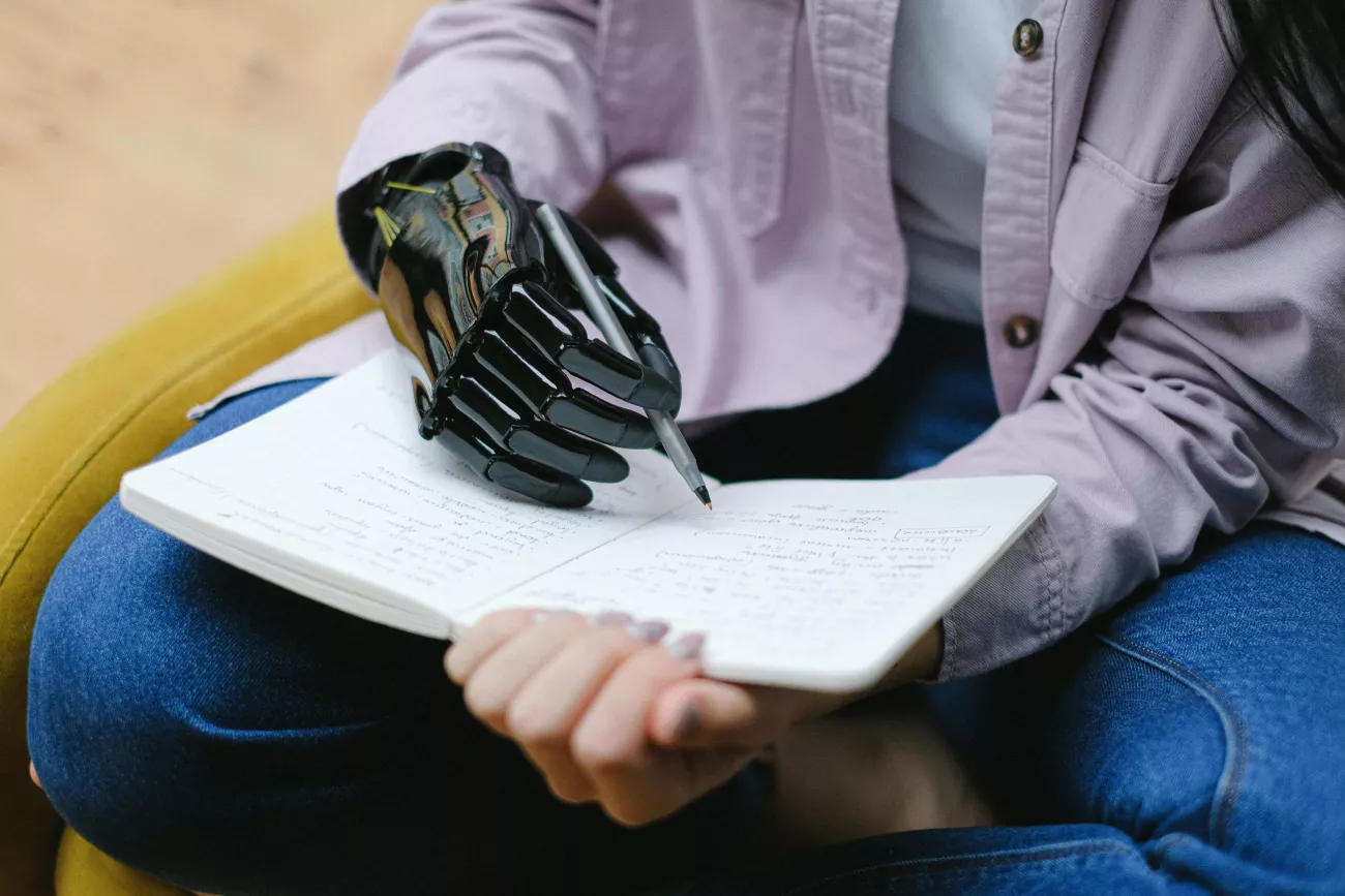 persona con disabilità motoria che scrive con mano robotica