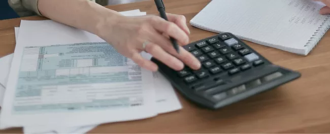 scrivania, calcolatrice, fogli e mano con penna